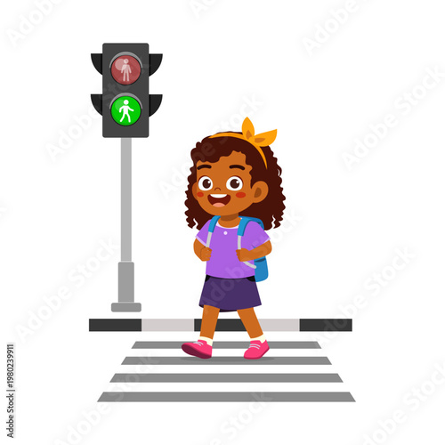 African American girl happily walks across a zebra crossing with a green pedestrian light in a cheerful mood