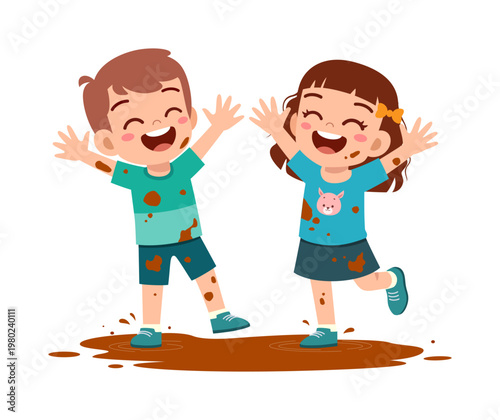 Joyful children a boy and a girl covered in mud smiling widely and laughing with arms up having messy outdoor fun