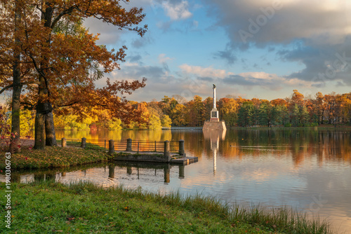 Stone pier on the shore of the Great Pond and the Chesme Column in the Catherine Park of Tsarskoye Selo on a sunny autumn day, Pushkin, Saint Petersburg, Russia