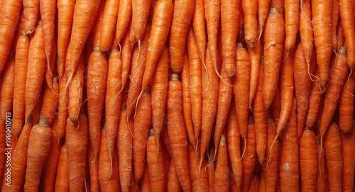 Assortment of orange carrots stacked together on a minimal white backdrop