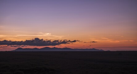 Leinwandbilder Lavendelfarbene Motive Sunset view of distant mountain and clouds over open savanna landscape  © vxnaghiyev