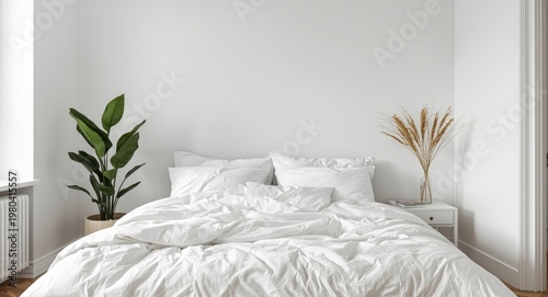White bedroom interior with a cushy bed and natural potted plant accent