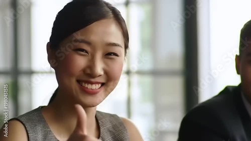 Young Asian Woman Gives Thumbs Up in Office Meeting.