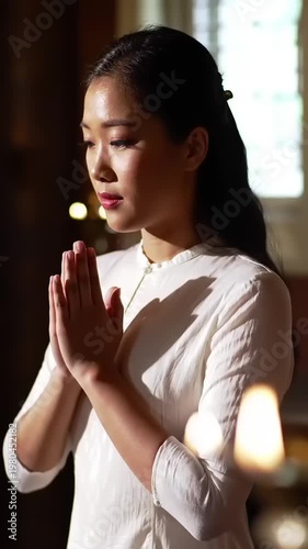 Young Asian Woman Praying with Hands Clasped in Church.