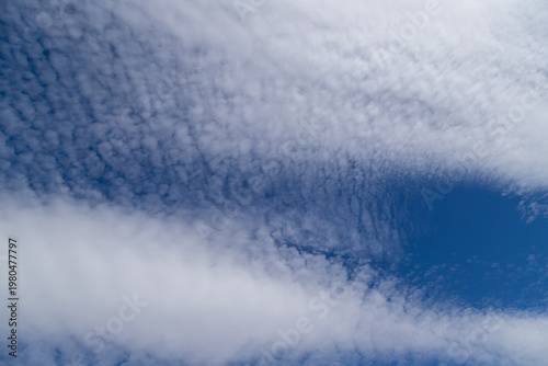 Altocumulus cloud formations create rippled texture and soft streaks across a...