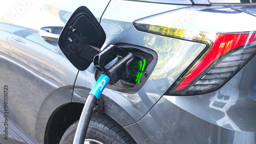 Schilderij op canvas Charging Electric Vehicle: A close-up view of an electric vehicle being charged, showcasing the charging cable connected to the car's charging port