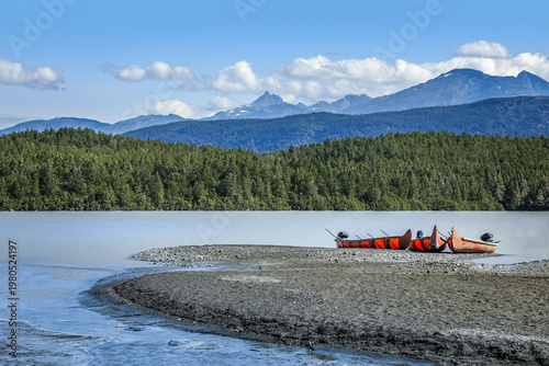 Peaceful Alaskan waters near the Chilkat Glacier with red canoes resting along the shoreline
