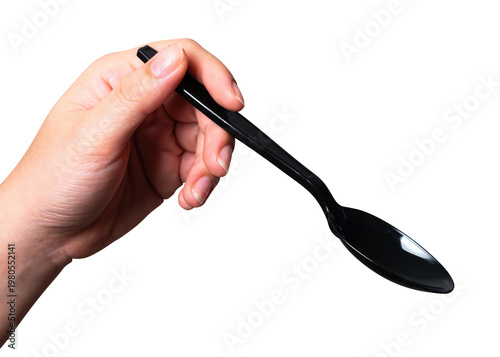 Female hand holding a black plastic spoon isolated on white background with clipping path.	
