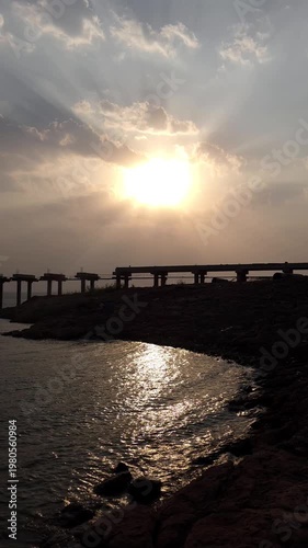Dramatic Sunset with Sun Rays Over Bridge and Water Reflection – Cinematic 4K Footage