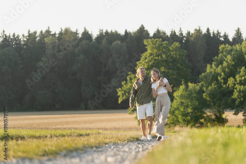 Billede på lærred Happy couple walking through open landscape enjoying summer light