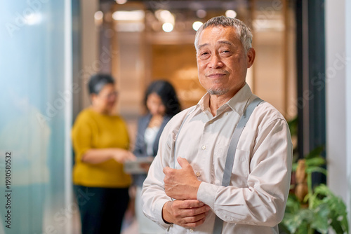 Portrait of senior businessman post in co-working office with team.
