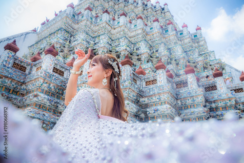 Close up of a young woman wearing traditional Thai dress with accessories standing at Wat Arun, a popular place for tourists around the world. Bangkok Thailand