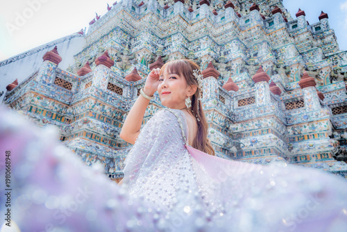 Close up of a young woman wearing traditional Thai dress with accessories standing at Wat Arun, a popular place for tourists around the world. Bangkok Thailand