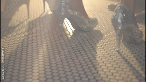  Elegant women's legs wearing high heels on a tiled floor with a moody cinematic atmosphere.
