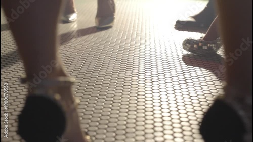  Elegant women's legs wearing high heels on a tiled floor with a moody cinematic atmosphere.
