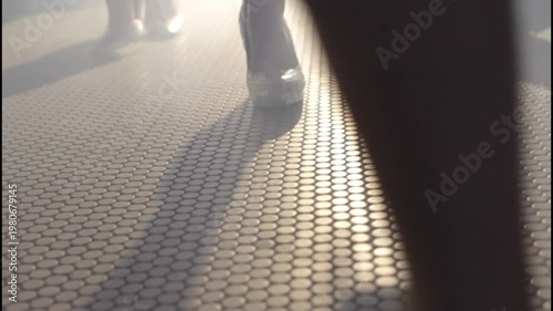 Elegant women's legs wearing high heels on a tiled floor with a moody cinematic atmosphere.
