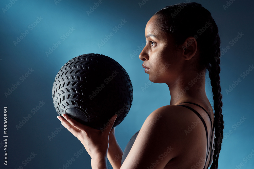 Naklejka premium Fitness, woman and thinking in studio with medicine ball, strength training or gear for HIT exercise. Active, person and gym equipment with reflection, vision or ready for workout on blue background.