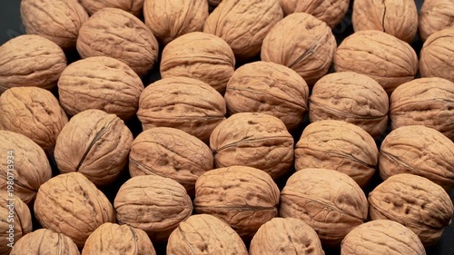 Rotating macro texture of whole organic walnuts in their shells on a dark background. Premium natural food concept for healthy diet projects.