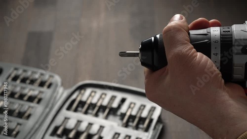 Battery cordless screwdriver and set screwdriver bits on a wooden background, close up