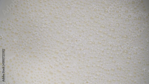 Fresh white milk with milk bubbles popping in the kitchen, close up