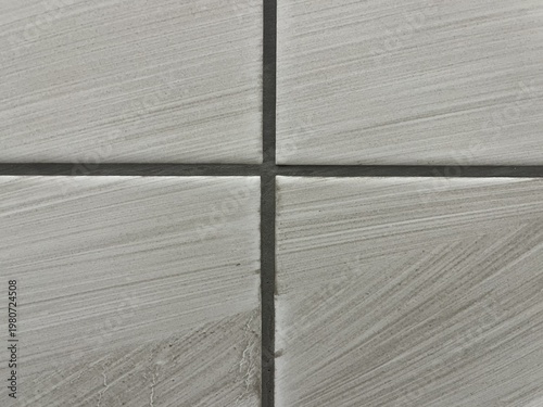Freshly applied dark grout on white ceramic tiles with messy wipe marks and cement dust