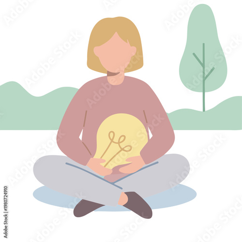 Woman sitting cross-legged outdoors with a lightbulb and notebook