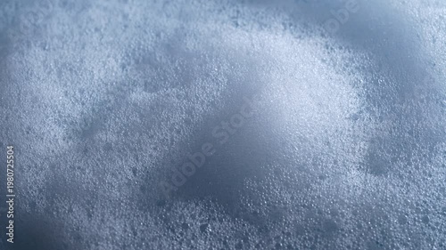 Close up of dense soap foam bubbles creating abstract texture background for cleaning hygiene and washing concept. Foamy soap bubbles rotates