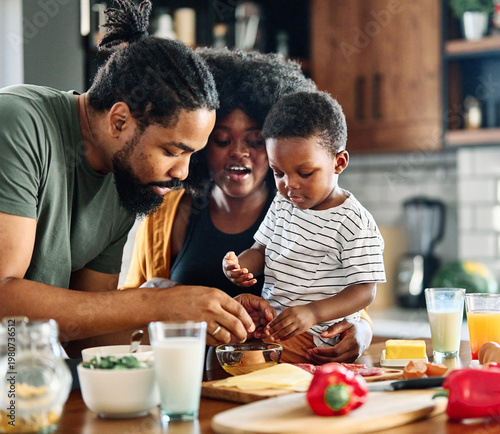 Portrait of mother, father and son preparing and eating breakfast in the kitchen at home