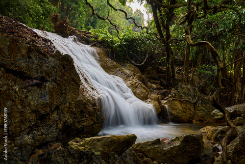 Scenic Waterfall Cascading Over Rocks in Lush Tropical Forest
