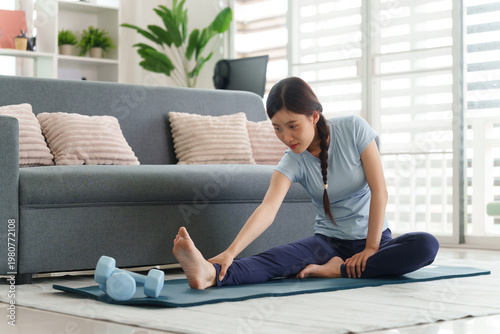 Tableau sur toile Asian woman stretching doing home yoga workout adult female achieving flexibilit