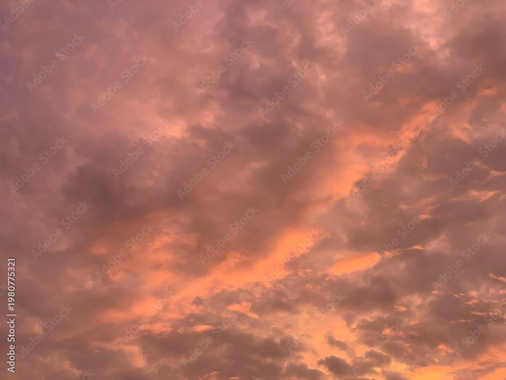 Fototapeta premium Dramatic fiery sky with glowing orange clouds at sunset, soft focus abstract texture, upward angle, rich light and shadow. Evokes intense mood, energy, and warmth. Perfect for backgrounds, nature, wea