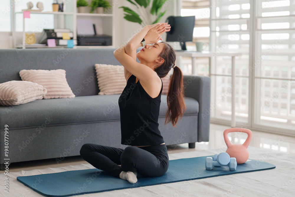 Fototapeta premium Asian adult woman practicing yoga stretching exercise home living room for mental physical wellness fitness healthy lifestyle balance relaxation wellbeing