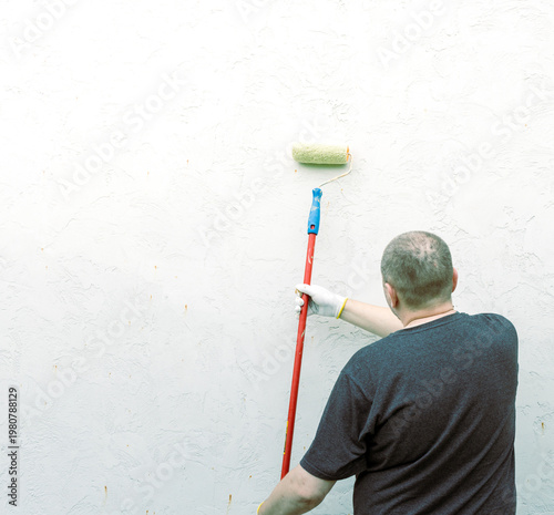 Wallpaper Mural Man paints wall with a roller Torontodigital.ca