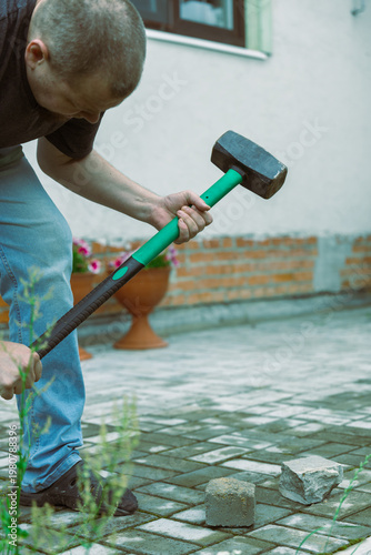 Wallpaper Mural Man breaks stone with heavy hammer on patio Torontodigital.ca
