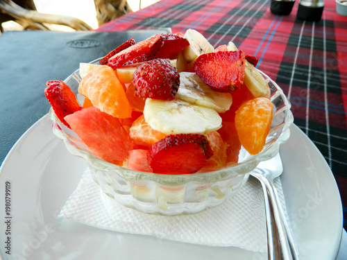 Fruit salad with strawberries, bananas, and oranges in clear glass bowl