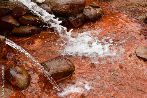 Clear water flows down rocks, creating white spray