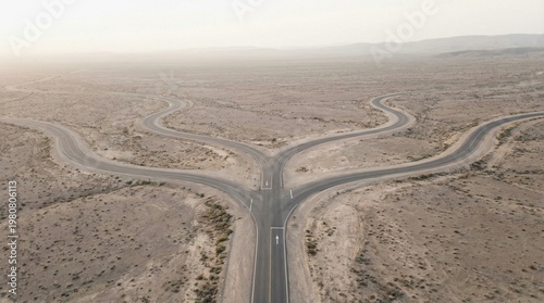 Aerial view of a lonely desert road branching into multiple paths, symbolizing a critical juncture of choice and the start of a new journey in a vast, arid landscape under an open sky