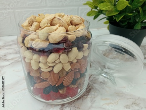 On the table, in a glass jar for snacks, a small amount of candied fruits and nuts are neatly laid out.