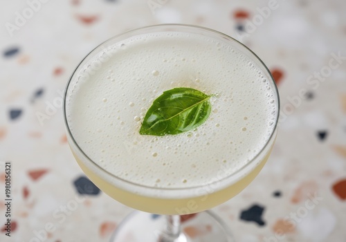 A refreshing gin basil smash cocktail in a coupe glass on terrazzo