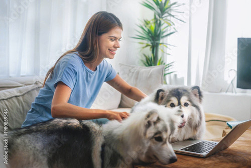 Young woman smiles with two dogs on a cozy couch