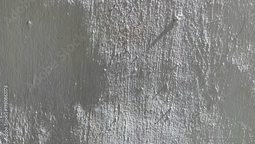 The surface texture of the gray concrete wall with scratches and peeling paint effects, gives a rough, industrial and artistic impression as a background.