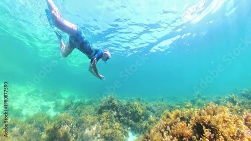 Woman snorkeling with a full-face mask over vibrant coral reef and sponge in El Nido, Palawan waters, enjoying a tranquil tropical underwater exploration and marine life viewing in Philippines islands