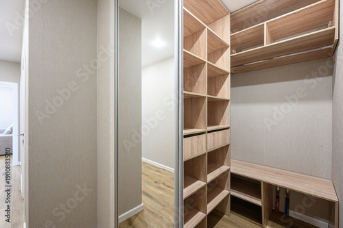 Photography modern walk-in closet with light wood shelving, open compartments, hanging rod,