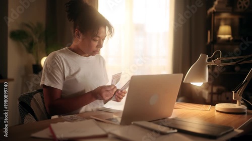 Focused african american woman counting dollar banknotes and dividing money into stacks at home office
