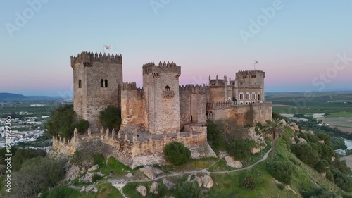 Aerial 4K view of the medieval Almodovar Castle in Cordoba, Spain at sunset. Golden hour light over the ancient fortress with scenic landscape.