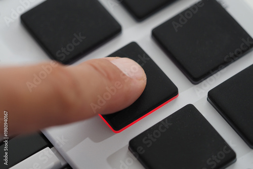 Fingers move over the pads on midi controller in a music studio as a person creates drums. Selective focus.