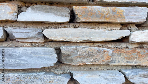Stacked stone wall displaying layered masonry texture for exterior facade cladding and architectural background design.