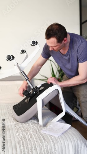 Adult male assembling office chair using hex key tool on wooden floor. Caucasian man hands screw chair lifting mechanism. Assembling office chair.