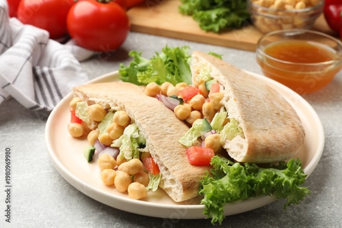 Pieces of pita bread with chickpeas and vegetables served on light grey table, closeup
