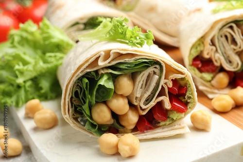 Pieces of wrap with chickpeas and vegetables served on table, closeup